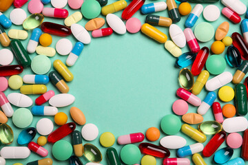 Frame made of many different pills on turquoise background, flat lay. Space for text