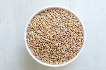 Wheat groats in a white bowl on a light background. Rustic style. Concept of healthy food. Horizontal orientation. Top view