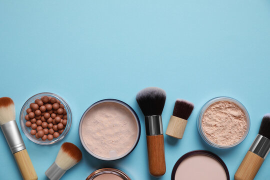 Different face powders and makeup brushes on light blue background, flat lay. Space for text