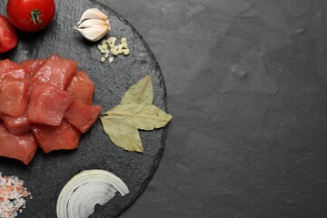 Raw beef meat and different ingredients for cooking delicious goulash on black table, top view....
