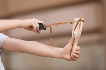 Little girl playing with slingshot outdoors, closeup