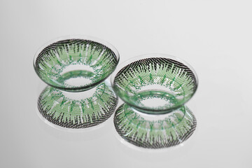 Two green contact lenses on mirror surface