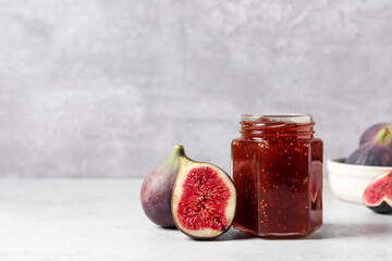 Jar of tasty sweet jam and fresh figs on white table. Space for text