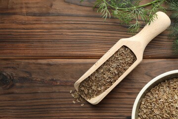 Scoop of dry seeds, bowl and fresh dill on wooden table, flat lay. Space for text