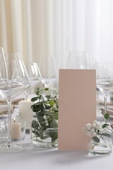Beautiful table setting with blank card and floral decor indoors, closeup