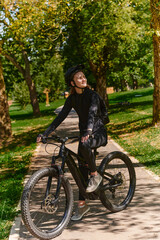 Obraz premium In the radiant embrace of a sunny day, a modern woman revels in the joy of cycling, her sleek bicycle and professional gear complementing her active lifestyle as she rides through the park
