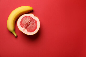 Banana and half of grapefruit on red background, flat lay with space for text. Sex concept