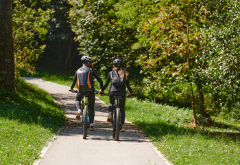 Obraz premium A blissful couple, adorned in professional cycling gear, enjoys a romantic bicycle ride through a park, surrounded by modern natural attractions, radiating love and happiness