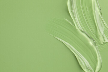 Sample of clear cosmetic gel on light green background, top view. Space for text