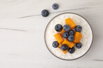 Bowl of delicious rice porridge with blueberries and pumpkin on white table, top view. Space for text