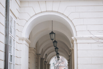 A long street gallery made of light stone with arches, columns and black lanterns. Lviv, Ukraine.