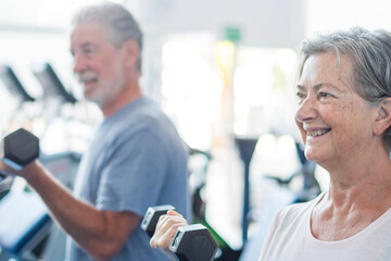 couple of two seniors training together at the gym with dumbbells in thei hand - heealthy and...