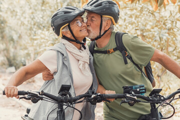 Couple of cute and sweet seniors in love enjoying together nature outdoors having fun with bikes....