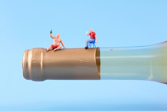 Miniature photography of people drinking at the mouth of wine bottles