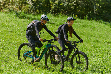 A blissful couple, adorned in professional cycling gear, enjoys a romantic bicycle ride through a park, surrounded by modern natural attractions, radiating love and happiness