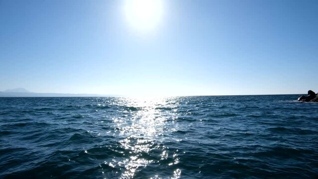 航行するボートから見た海の風景、青空と太陽の光、波しぶき