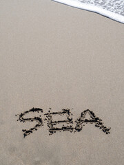 砂浜の波打ち際に書かれた「SEA」の文字。
