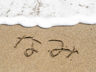 砂浜の波打ち際に書かれた「なみ」の文字。
