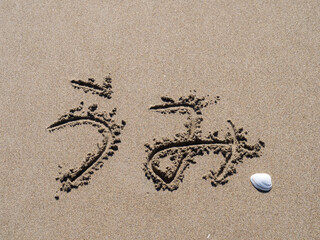 砂浜に書かれた「うみ」の文字と貝殻。
