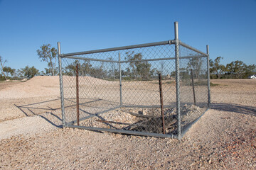 An abandoned underground opal mine with a safety fence and damaged environment in Lightning Ridge in New South Wales, Australia.