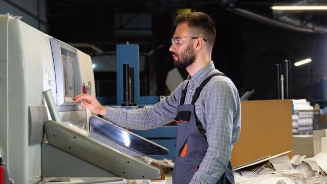 Technician operator checking input and output status on touchscreen front display monitor station at print plant factory