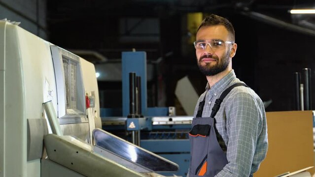 Portrait of technician operator near modern offset printing machine.