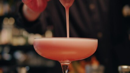 Bartender make a cocktail for guest in the bar. Pink foamy sour alcohol drink . Barman is doing drinks close-up. Modern bar with many varieties of cocktails and drinks. - Powered by Adobe