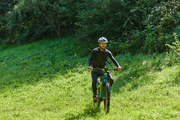 Obraz premium In the radiant glow of a sunny day, a fitness enthusiast, donned in professional gear, pedals through the park on his bicycle, embodying strength and vitality in a dynamic outdoor workout