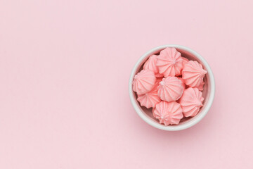 A bowl with fresh pink meringue on a pink background. Space for text.