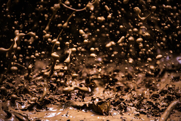 Brown mud flies from an offroad tire, macro