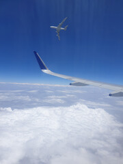 An view of an aircraft flying past another aircraft, viewed from an aircraft window.