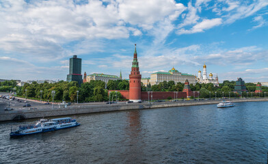 View of Kremlin with Vodovzvodnaya tower, Grand Kremlin Palace from repaired Bolshoy Kamenny Bridge in Moscow city on sunny summer day. Cruise ship sails on the Moscow river