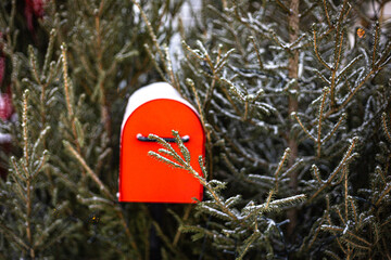 Red postbox on the background of green Christmas tree, red mailbox for letters to Santa Claus and a green Christmas tree