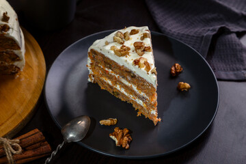 Carrot cake with butter cream and walnuts on a dark background