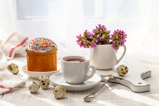 Easter still life with painted eggs, Easter cake and tea in a cup on the windowsill on a sunny day