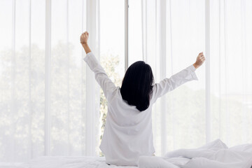 Woman stretching in bed after wake up. stretching and happy woman waking up in the morning after...
