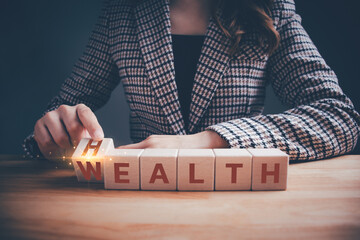 Businesswoman hand flipping wooden blocks between HEALTH and WEALTH text. Investment in life...