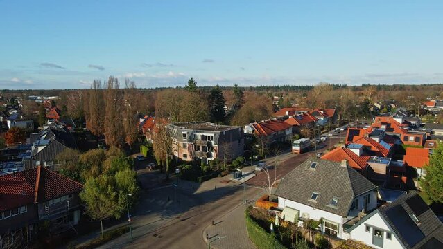 Low aerial of beautiful suburban neighborhood with two driving cars and a cyclist on the calm road