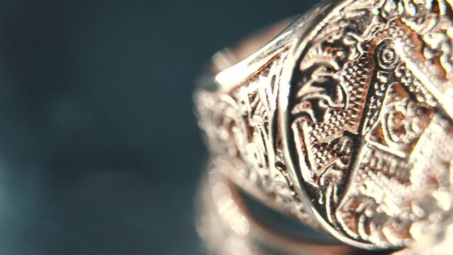 A macro detailed shot of a golden textured freemasons ring, on a rotating stand, mirror reflection, illuminati symbol, professional studio light, 4K video