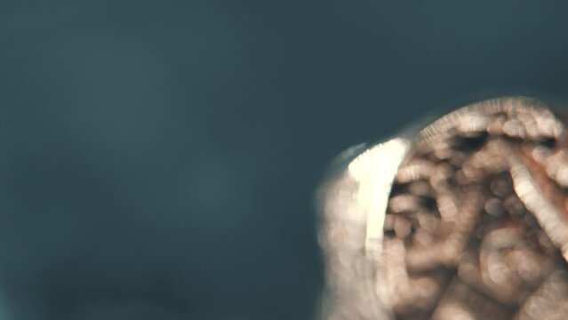 A macro detailed tilt up shot of a golden textured freemasons ring, on a rotating stand, mirror reflection, illuminati symbol, professional studio lighting, 4K video
