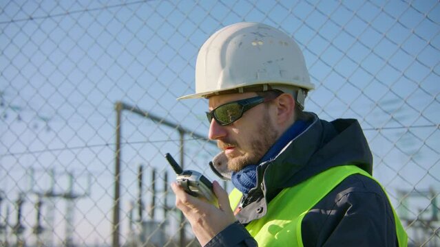 Engineer on location communicating with colleagues via walkie talkie