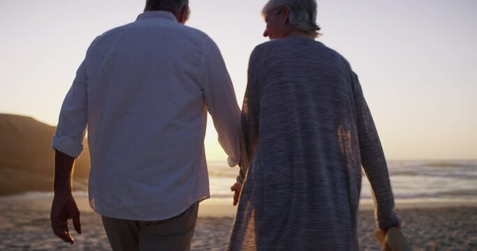 Senior couple, walking on beach and hand holding in sunset and married on holiday, outdoor and back. Retirement, elderly or love for commitment, bonding together or care for romantic relationship