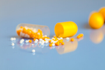 Vitamin capsule on blue background, close-up, yellow pill, no people.