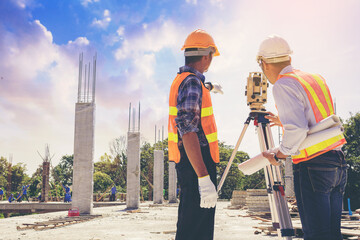 Engineer or surveyor worker working with theodolite transit equipment at outdoors construction site.