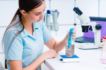 young woman in ecology laboratory examining water samples from natural sources
