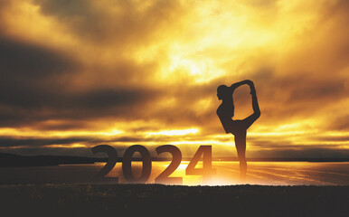 New year 2024 fitness healthy woman yoga with sunset sky background