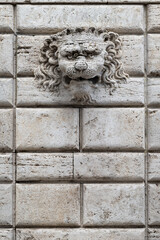 Decorative lion's head mounted on a stone wall in Italy