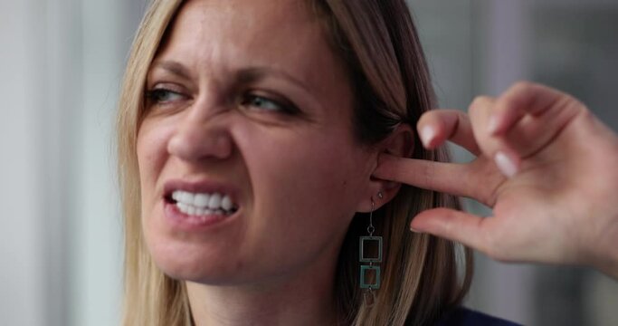 Nervous young woman scratching ear with finger