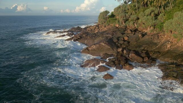 Aerial Drone Shot Rotating Around Rocky Shoreline in Tropical Sri Lanka with Waves Crashing 60 FPS