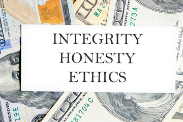 INTEGRITY HONESTY ETHICS text, a word written on a white business card against a background of money